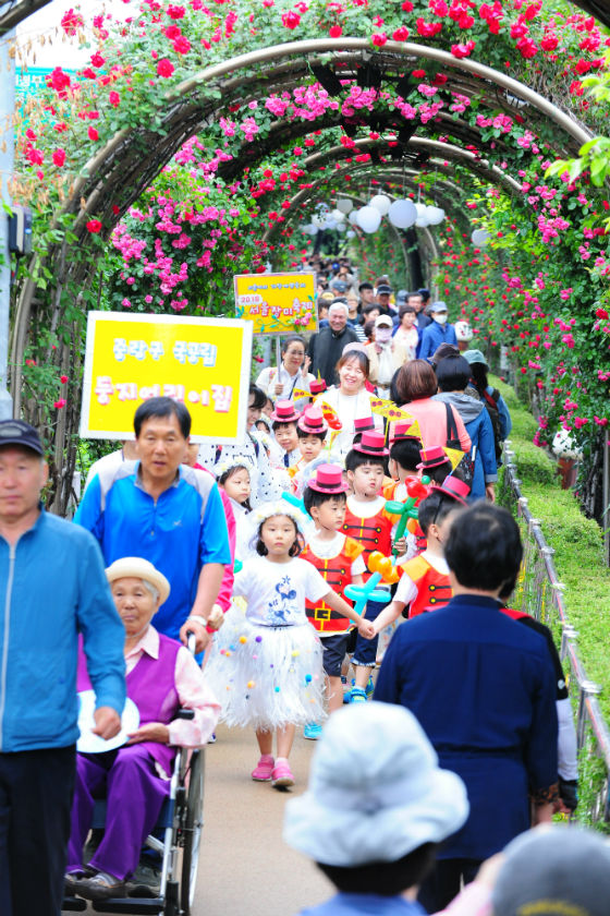장미 퍼레이드에 참여한 둥지 어린이집 원아들이 손을 잡고 장미터널 아래를 행진하고 있다