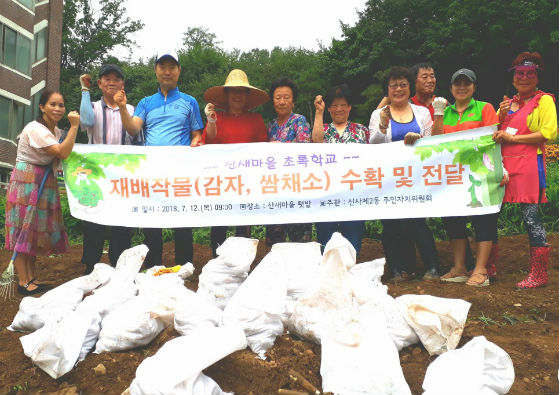 신사2동 주민자치위원회와 산새마을 주민들이 작물을 수확하고 기념 촬영을 하고 있다