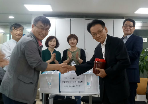 에너지자립마을 김선구 회장(왼쪽)이 유해우 나라사랑채 입주민 대표에게 주민들이 직접 만든 고추장을 선물하고 있다