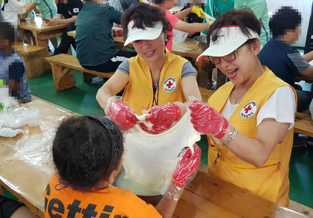 참가자와 적십자 봉사원이 치즈만들기 체험을 하고 있다