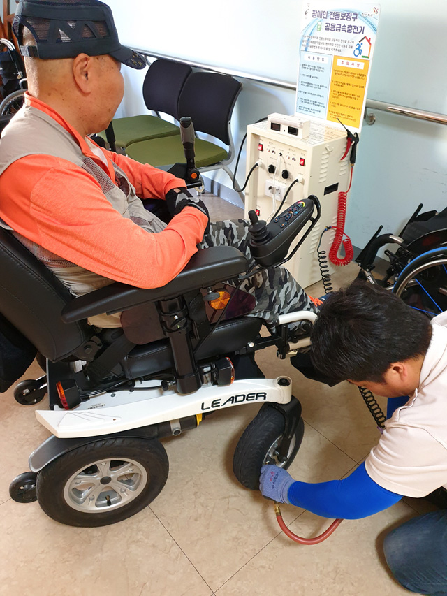 장애인복지관 내 장애인전동보장구 공용충전기에서 휠체어에 바람을 넣고 있다.