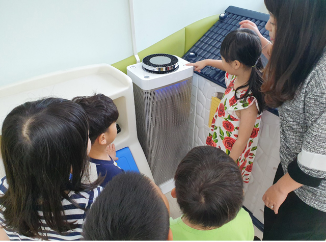 쾌적한 실내환경 유지를 위해 어린이집에 설치한 공기청정기를 아이들이 직접 작동해보고 있다.