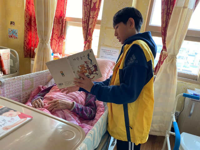 청소년 자원봉사자가 강동구 어느 요양원에 입원 중인 어르신에게 책을 읽어주는 봉사활동을 하고 있다