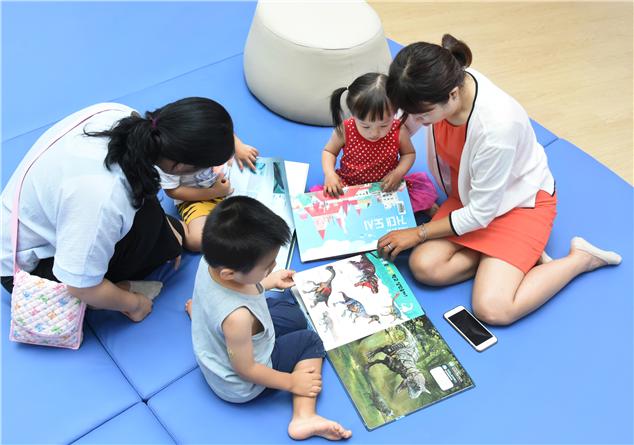 엄마와 아이들이 중랑숲어린이도서관에서 그림책을 읽고 있다