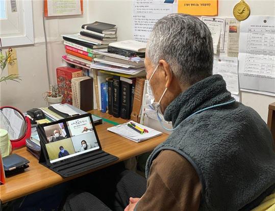 집에서 태블릿PC로 온라인에 참여한 어르신이 종로노인복지관장 정관스님을 비롯해 함께 참여한 어르신들에게 안부 인사하고 있다