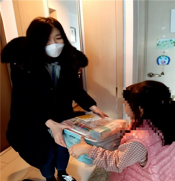 주민센터 관계자가 예비 초등학생에게 책가방을 전달하고 있다 