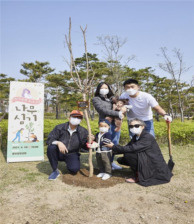 아기탄생 축하기념 나무심기 행사 참여자들이 나무를 심고 기념 촬영하고 있다