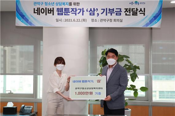 박준희 구청장이 작가 삼으로부터 기부금 1,000만 원을 전달받고 있다